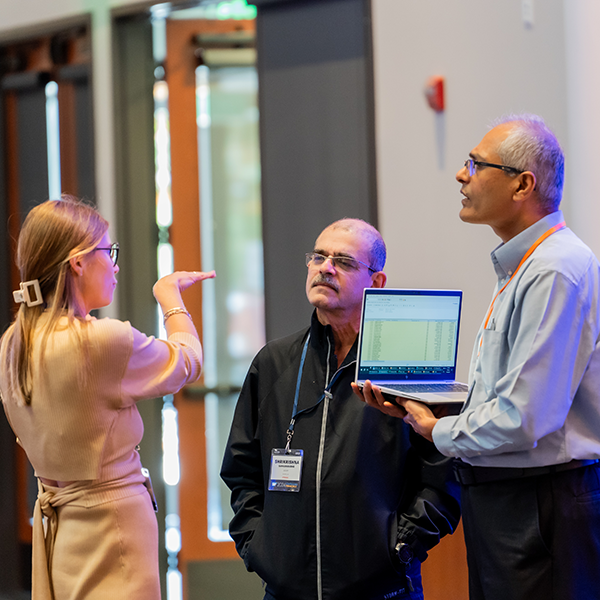 three people discuss sap while holding laptop